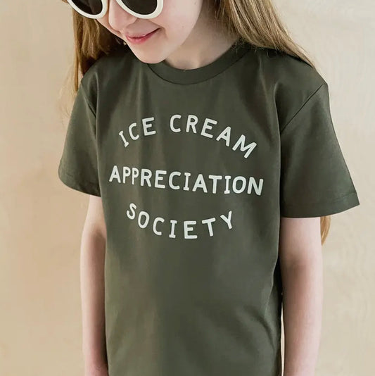 Girl wearing khaki green T-shirt with ice cream appreciation society writing in white on front