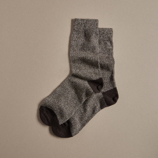 Dark brown and light brown marl speckled merino wool socks with dark brown heel on a beige background 