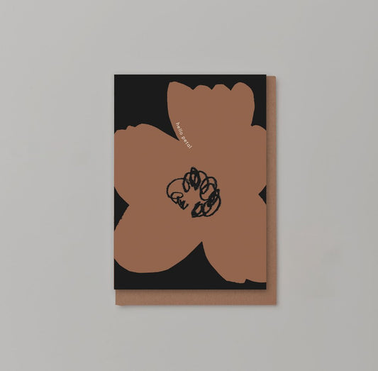 Black greetings card with large brown flower with a swirly black centre and hello petal printed in white lowercase font along the side of the top petal with a brown envelope