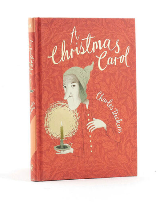 Red hard backed book with an illustration of a man holding a candle A Christmas Carol in gold coloured cursive writing and Charles Dickens in white writing