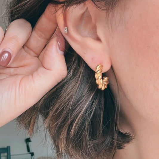 Gold twisted rope hoop earring worn in ear