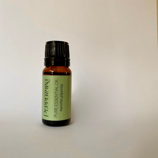 Small amber coloured glass bottle of essential oil with black lid and green label with peppermint pure essential oil mentha piperita printed in dark grey letters 