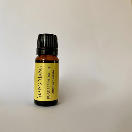 Small amber coloured glass bottle of essential oil with black lid and yellow label with ylang ylang pure essential oil cananga Odonata printed in dark grey